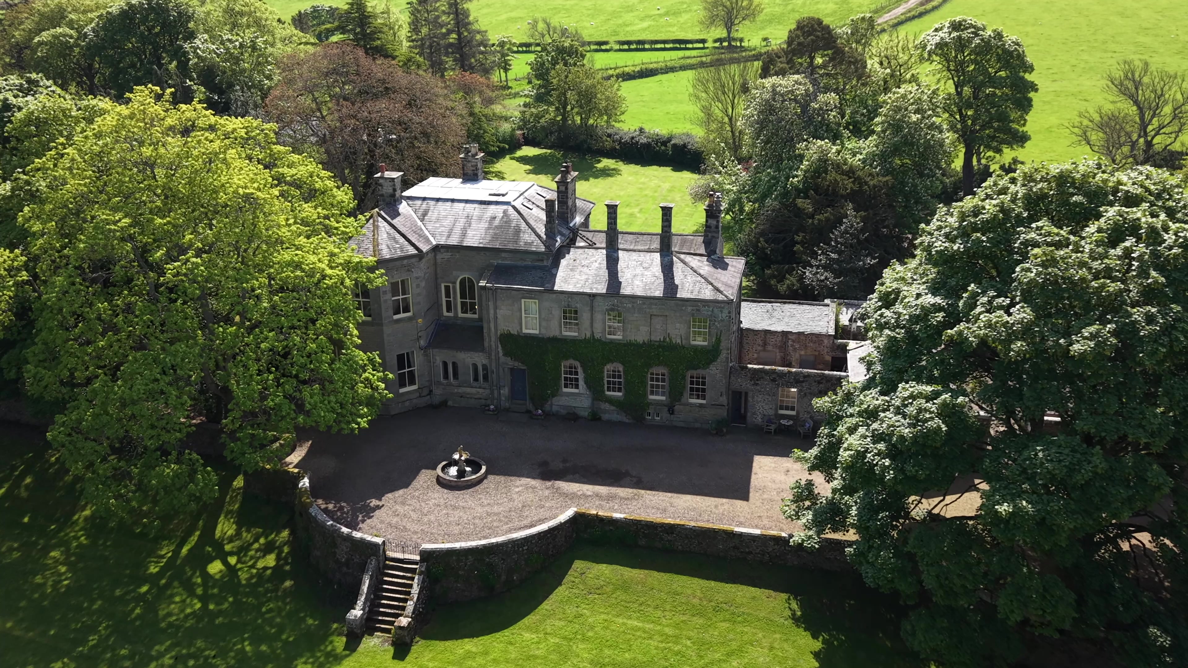 Aerial view of the stone Old Rectory, its courtyard and mature grounds in Ingram.