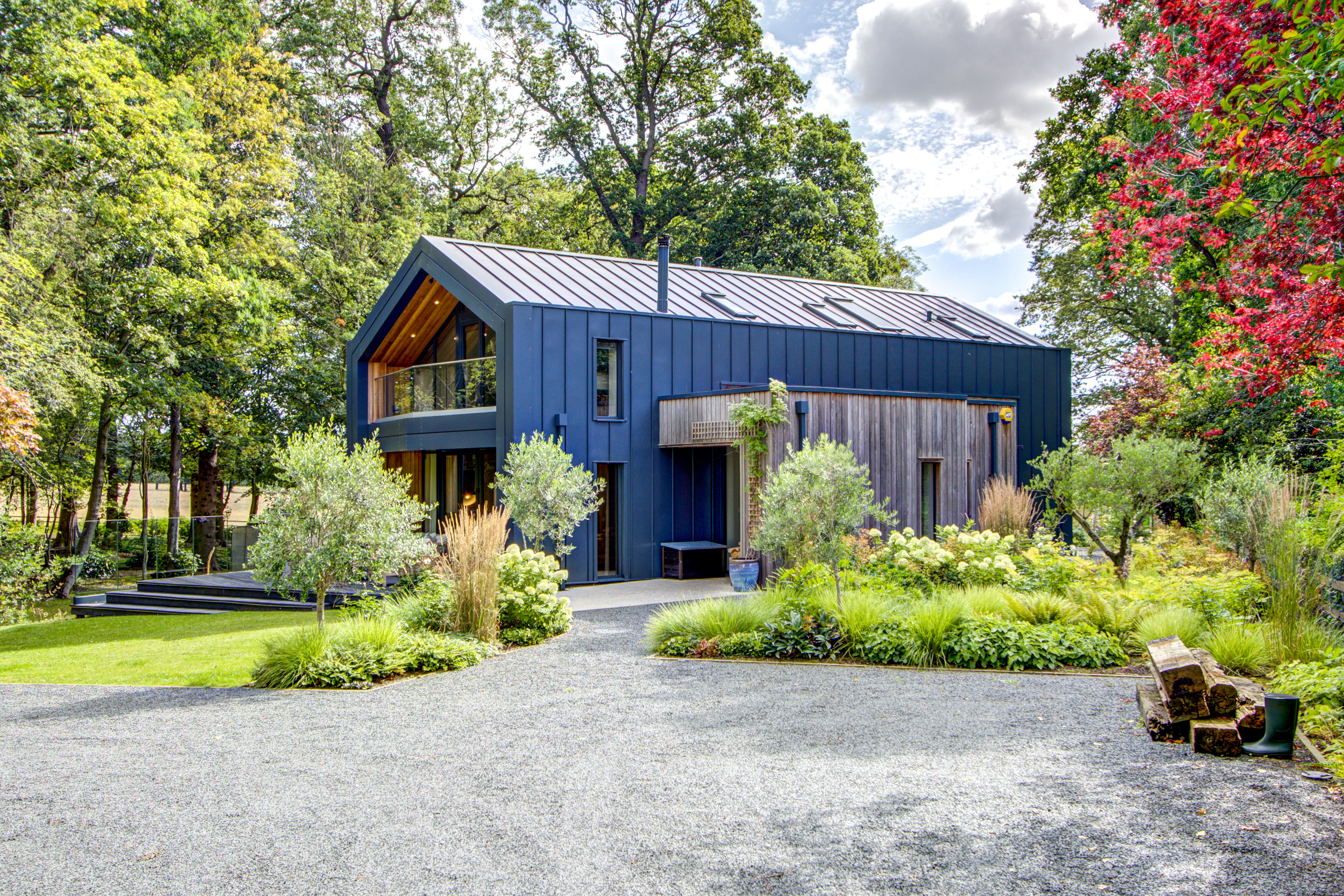 Contemporary timber and metal-clad exterior of High Beeches surrounded by landscaped gardens.